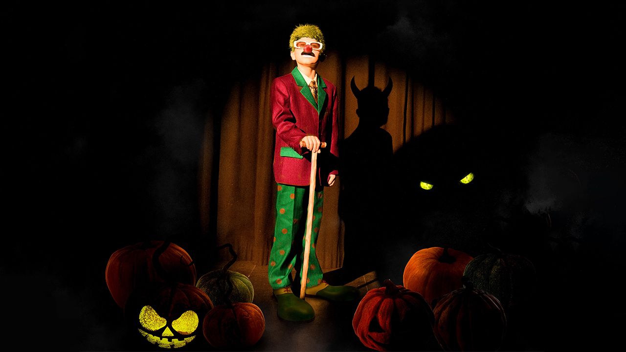 Ein Clown bei der Halloweenvorstellung mit zwei Masken auf der Bühne