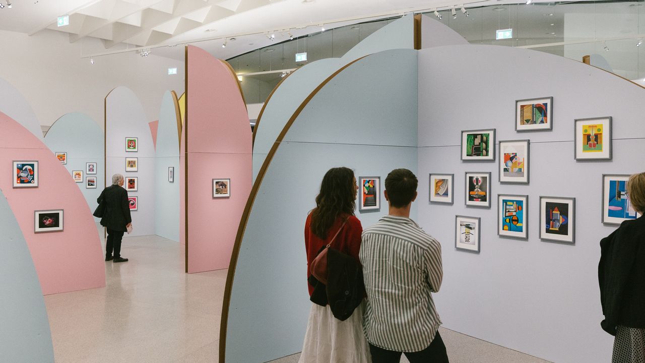 Ein Pärchen besichtigt eine Ausstellung mit Gemälden auf der Wand