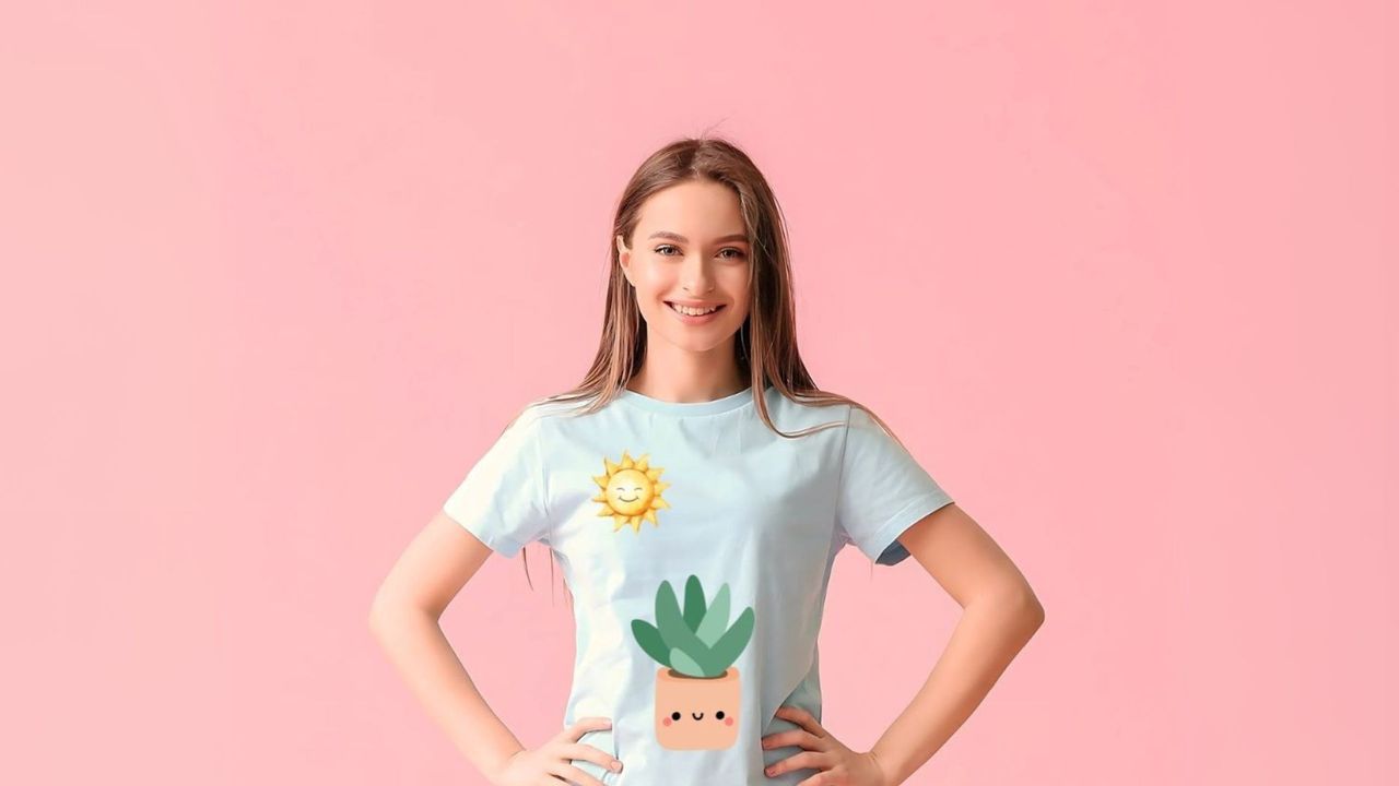 © PRINTSHOP Frau trägt ein individuell bedrucktes T-Shirt und steht vor einem rosafarbenen Hintergrund