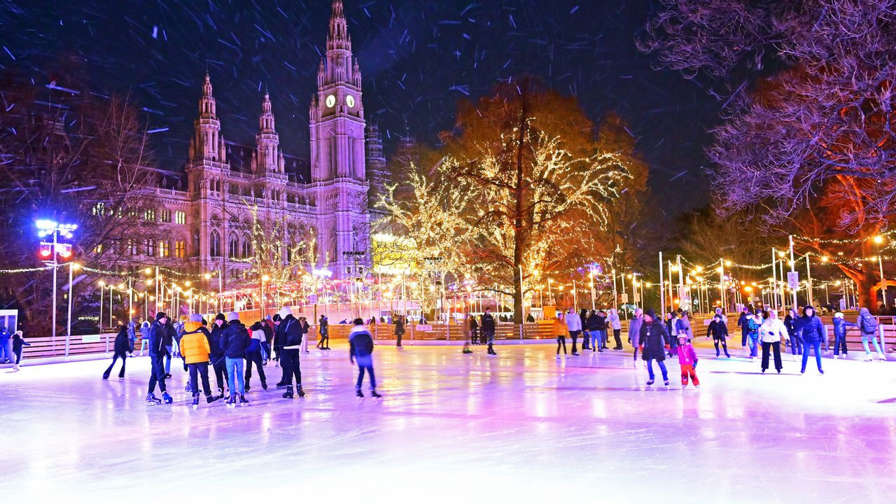 volle Eislauffläche und im Hintergrund das beleuchtete Wiener Rathaus