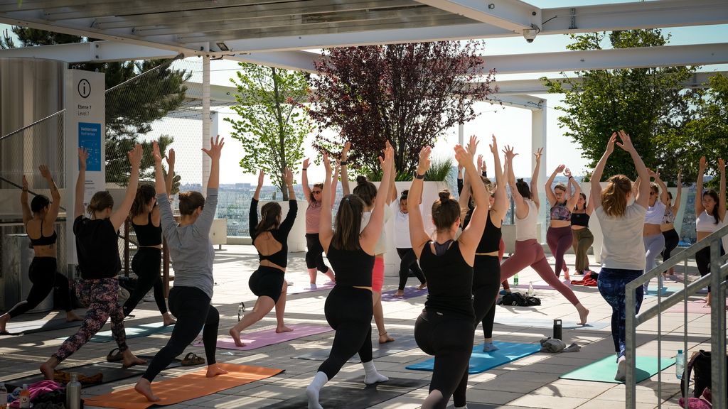 Personen machen Yoga-Übungen auf einer Dachterrasse