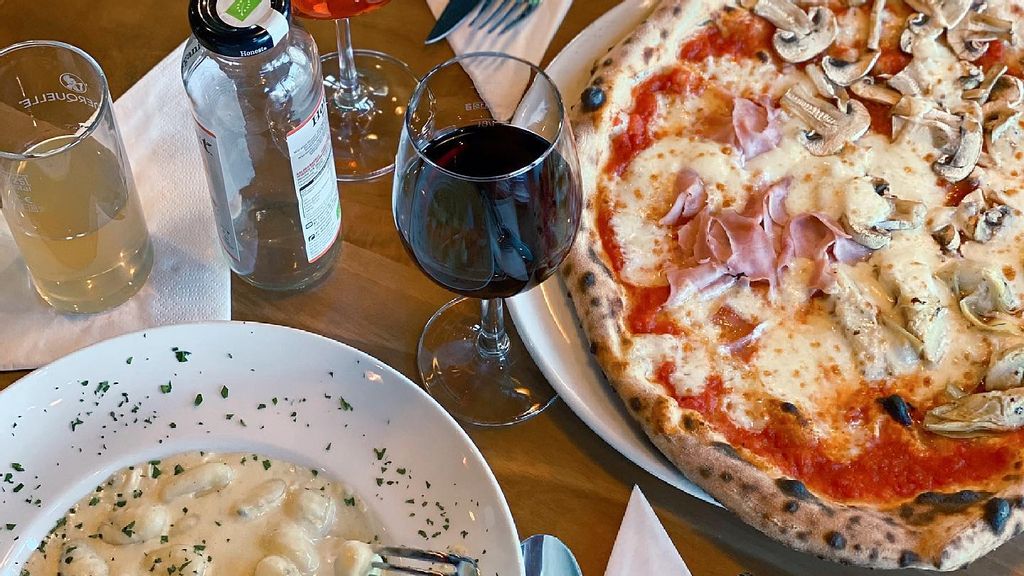 Pizza und Gnocchi dazu Getränke serviert im Restaurant Al Capriccio