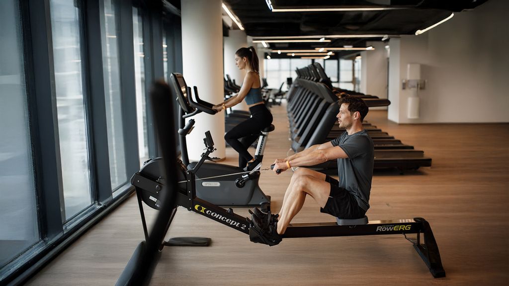 Eine Frau auf dem Cross-Trainer und ein Mann auf der Rudermaschine im Fitnessstudio.