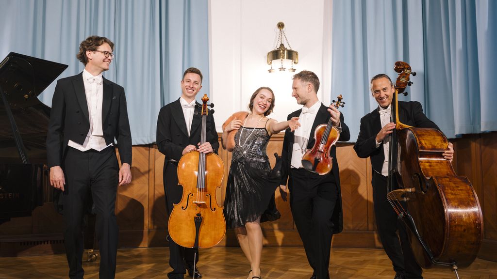 Fünf Musiker*innen mit Streichinstrumenten und Klavier auf einer Bühne