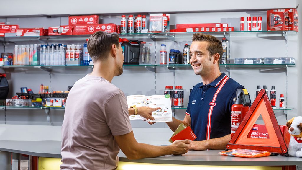 Ein Mann beim Einlösen des Vorteils, während der Shopleiter ihm die Angebote zeigt