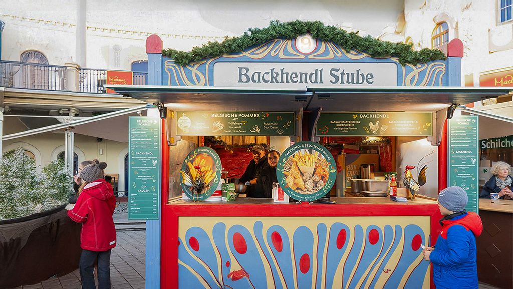Weihnachtsmarkt-Hütte mit zwei Verkäufern und mehreren Personen, die darum herumstehen.