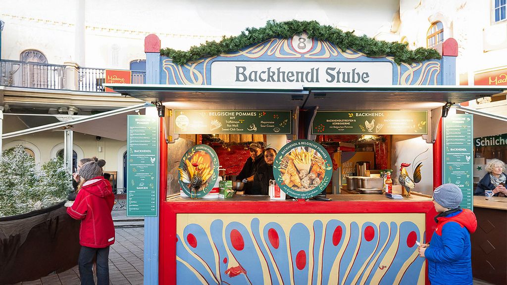 Weihnachtsmarkt-Hütte mit zwei Verkäufern und mehreren Personen, die darum herumstehen.