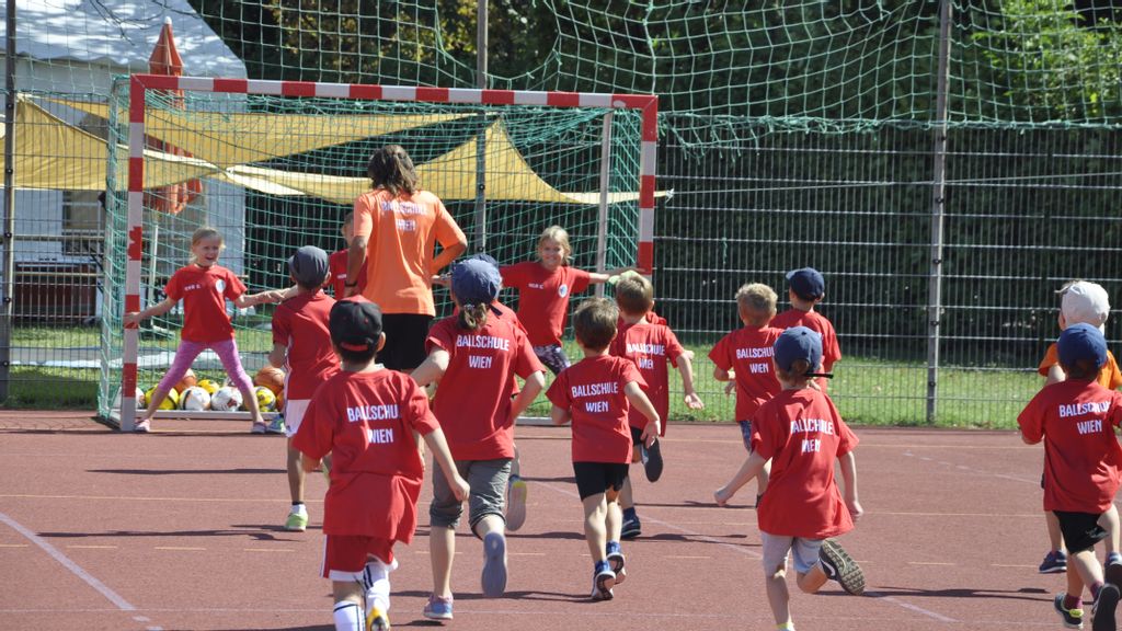 Gruppe an Kindern am Sportplatz beim Fußballspielen