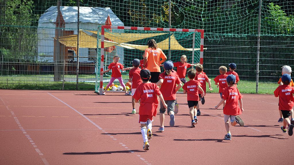 Gruppe an Kindern am Sportplatz beim Fußballspielen