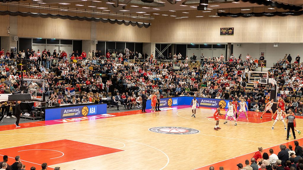 Basketballspiel in einer gut besuchten Sporthalle mit Spielerinnen auf dem Spielfeld