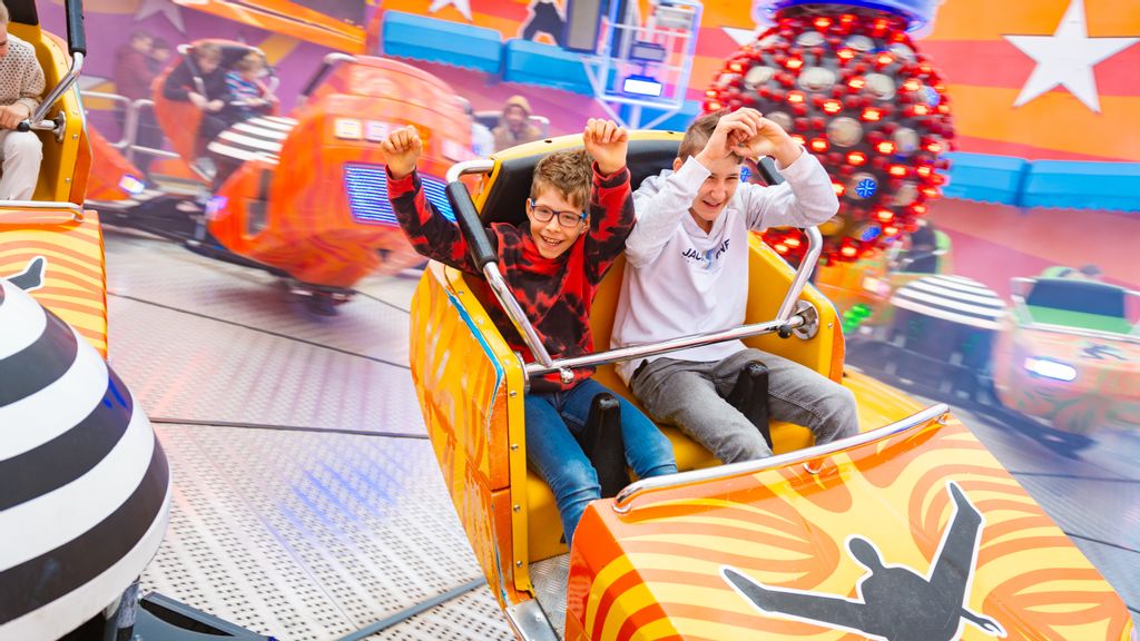 Zwei Burschen in dem bunten Sitz, der sich während einer Fahrt im Break Dance dreht