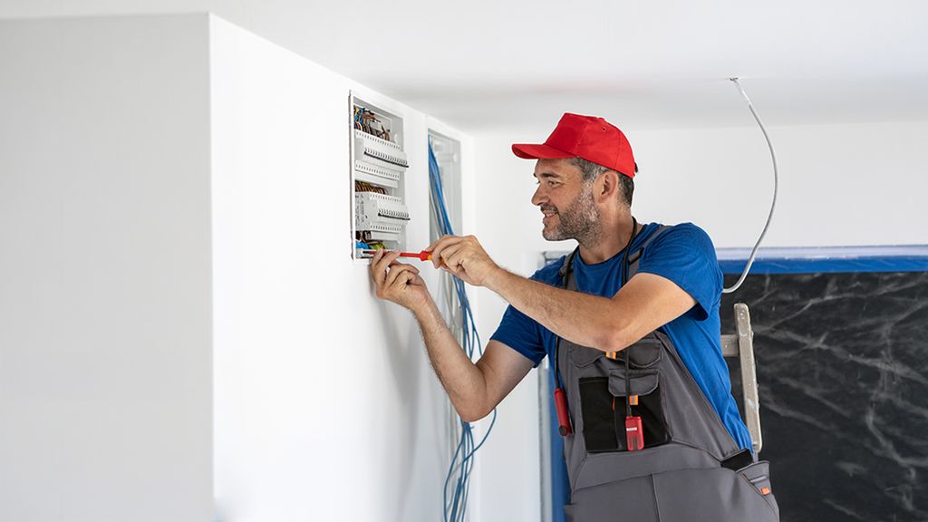 Ein Elektriker schraubt an Sicherungskasten