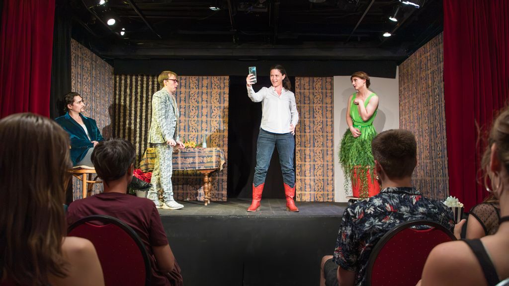 Vier Personen stehen in Kostümen auf einer Bühne und spielen ein Theaterstück