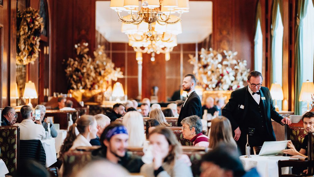 Gäste im prunkvollen Cafe und zwei Kellner beim Servieren