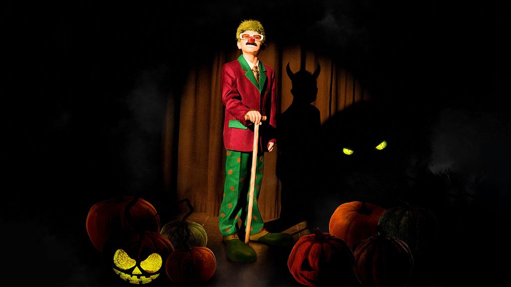 Ein Clown bei der Halloweenvorstellung mit zwei geschnitzten Kürbissen auf der Bühne