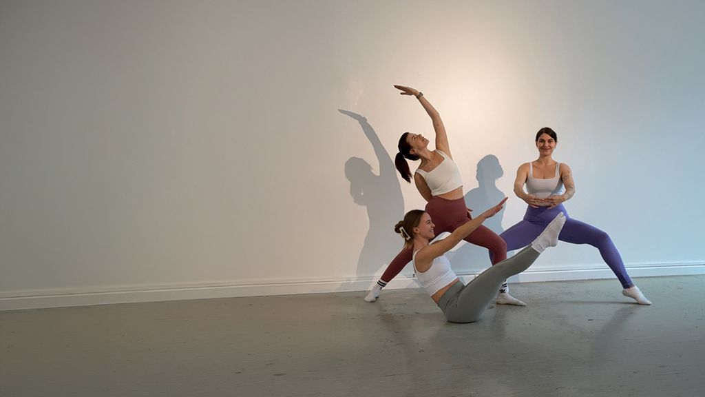 Drei Frauen in Yoga-Positionen vor einer weißen Wand