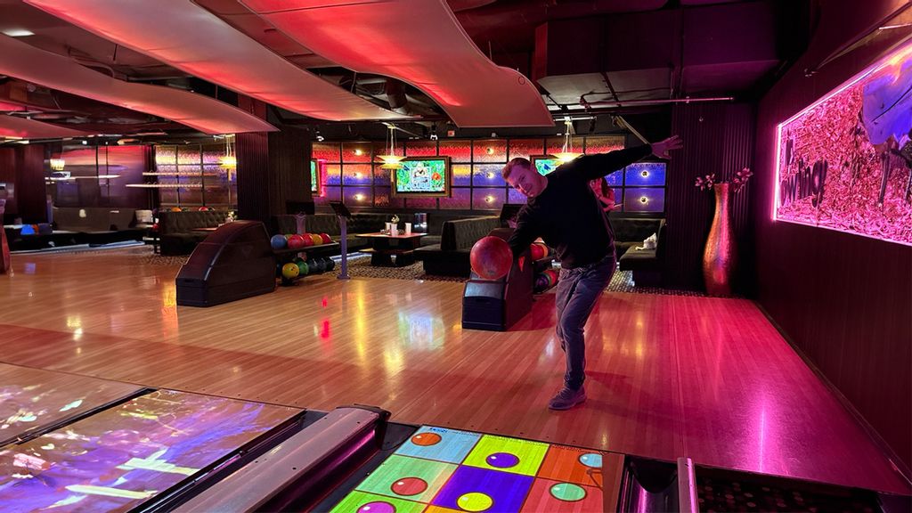 Mann bowlt in einer beleuchteten Bowlinghalle