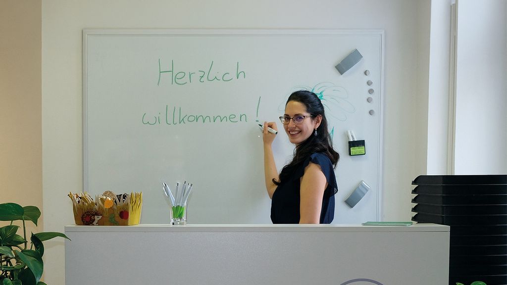 Frau in einem Kurs schreibt auf eine weiße Tafel und lächelt