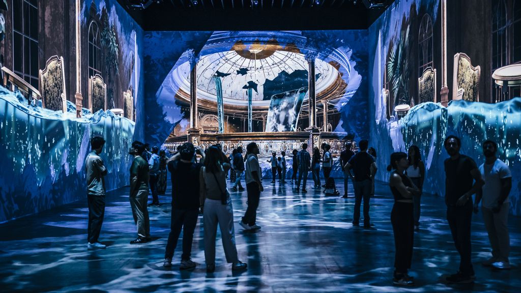 Eine Familie steht vor einer Leinwand bei einer immersiven Ausstellung von Titanic