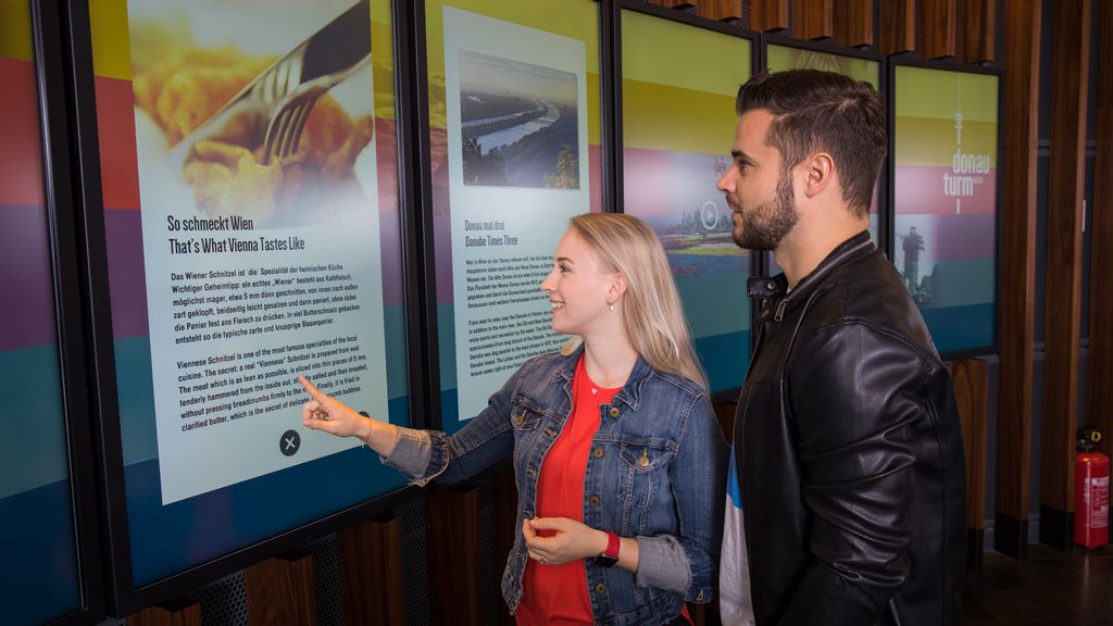 Eine Frau und ein Mann betrachten einen Videoscreen im Donauturm