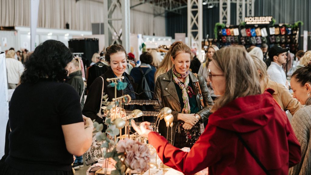 Besucher*innen stöbern an einem Verkaufsstand am Designmarkt.