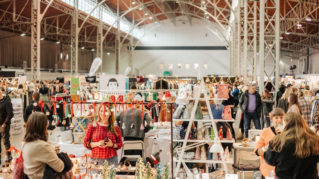 Besucher*innen des Edelstoff Designmarkts erkunden die Produkte eines Ausstellungstandes