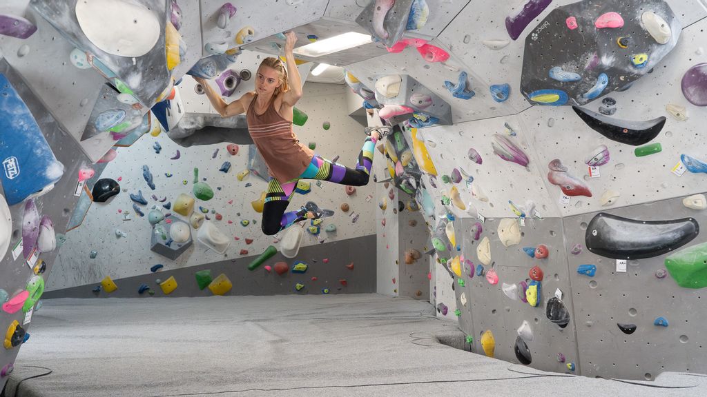 Frau beim Bouldern in einer Halle