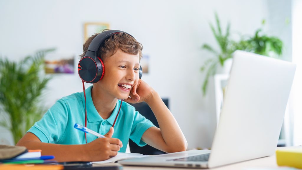 Junge trägt Kopfhörer, sitzt vor einem Laptop und lernt