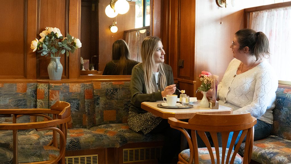 Zwei Frauen sitzen bei Café und Kuchen an einem Tisch