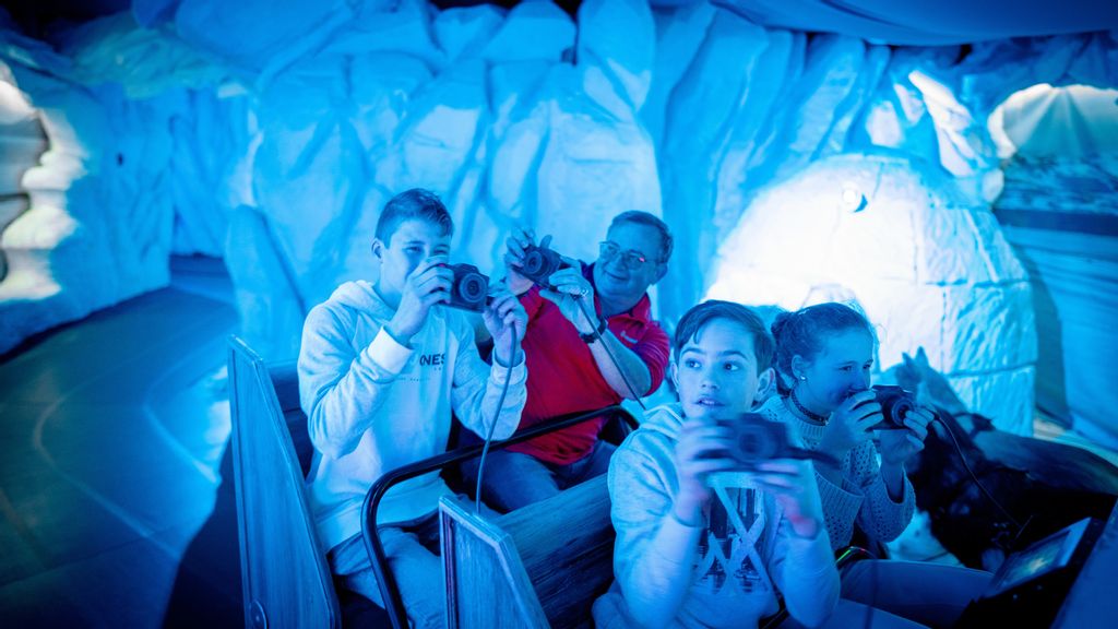 Zwei Kinder und zwei Erwachsene in einer Holzbahn fotografieren das winterliche Ambiente