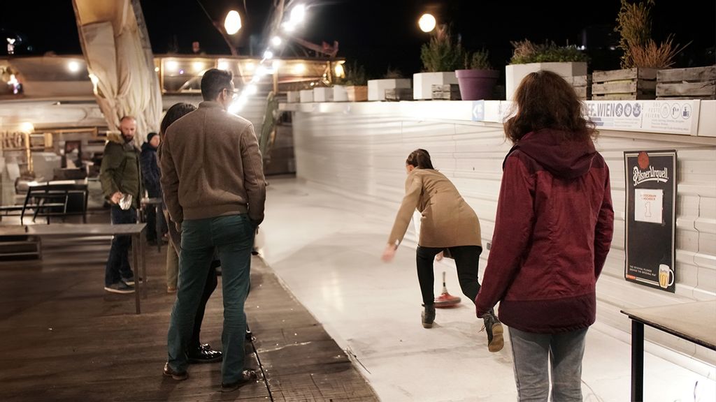 Mehrere Personen beim Eisstockschießen am Badeschiff