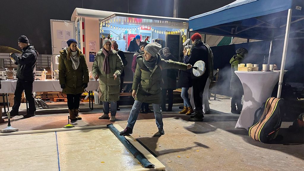 Mehrere Personen beim Eisstockschießen in Hernals vor einem Punschstand