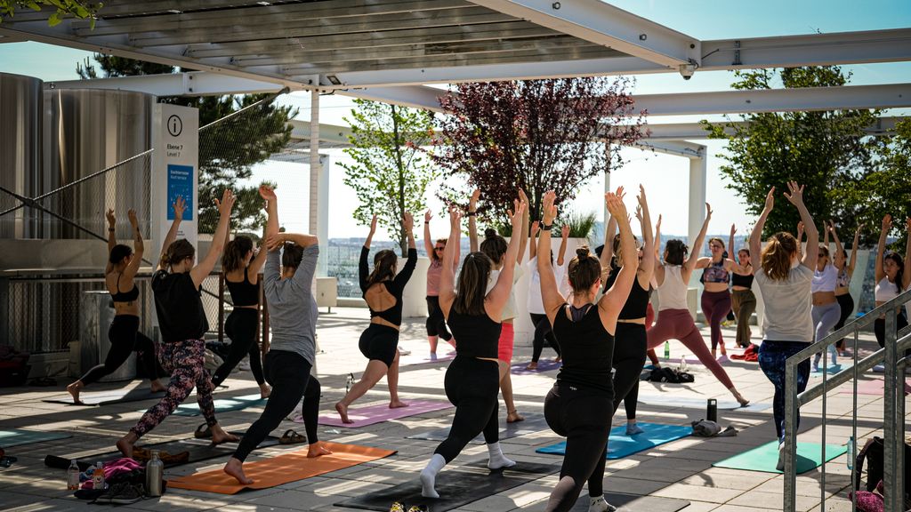 Kurs-Teilnehmer*innen beim Ausführen einer Yoga-Übung in der Rooftop-Bar