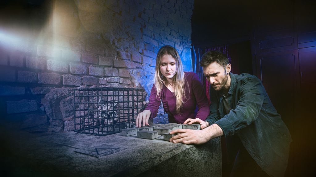 Eine Frau und ein Mann in einem Escape Room beim Lösen eines Rätsels mit Bausteinen