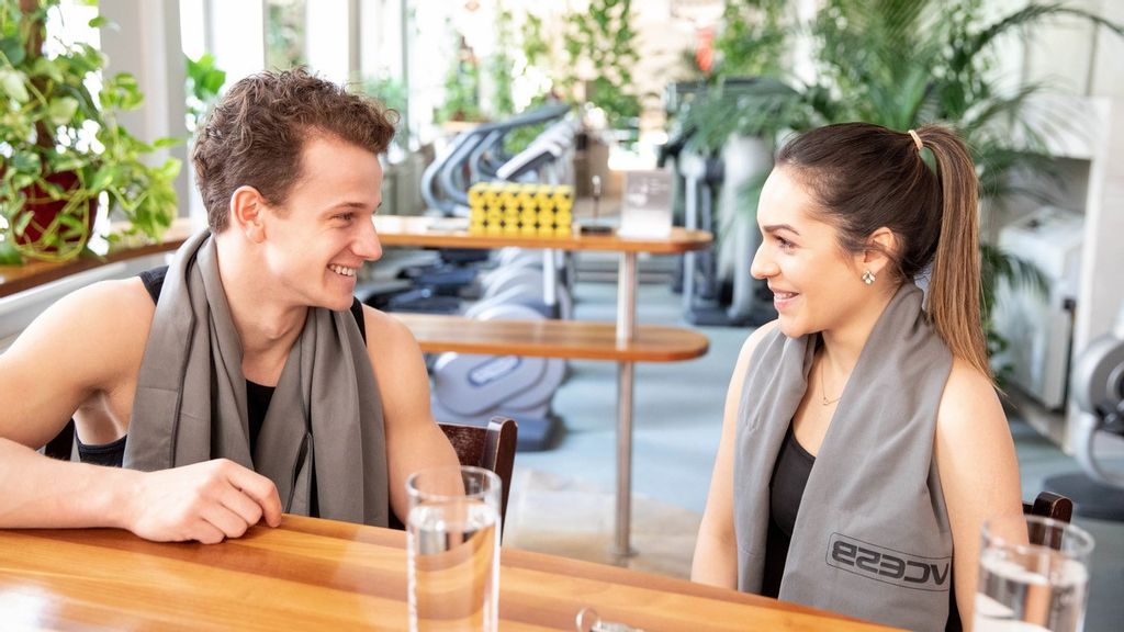 Ein Mann und eine Frau sitzen im Eingangsbereich eines Fitnessstudios