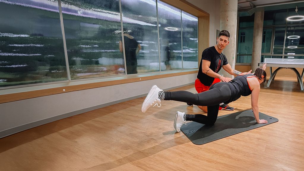 Personaltrainer unterstützt eine Frau beim Training auf der Matte