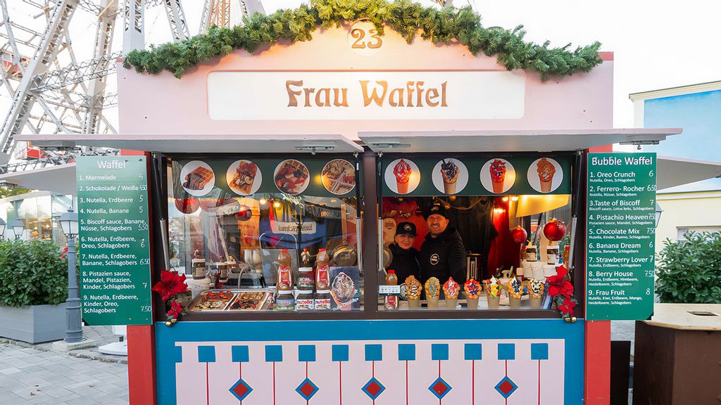 Weihnachtsmarkt-Hütte mit einem Verkäufer und einer Verkäuferin.