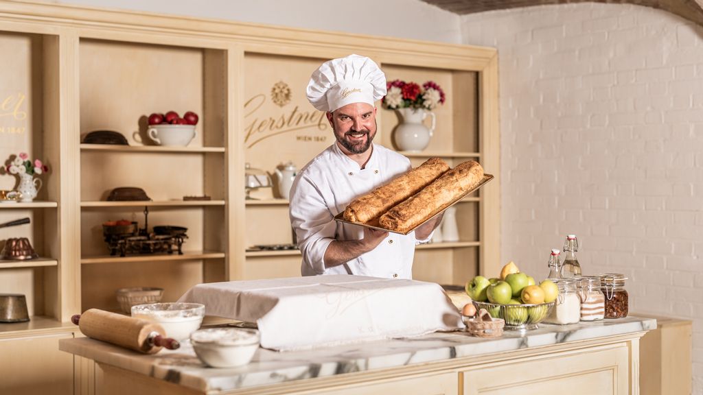Der Bäcker präsentiert in weißer Schürze zwei Laib Brot