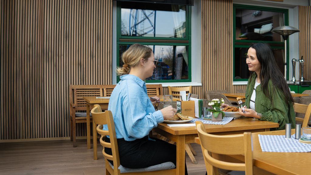 Zwei Frauen sitzen im Gastgarten vom Gösser Eck und essen 
