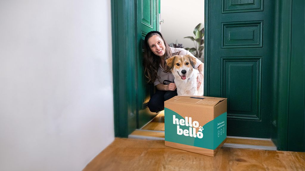 Frau mit Hund steht im Eingangsbereich ihrer Wohnung mit einem HelloBello Paket