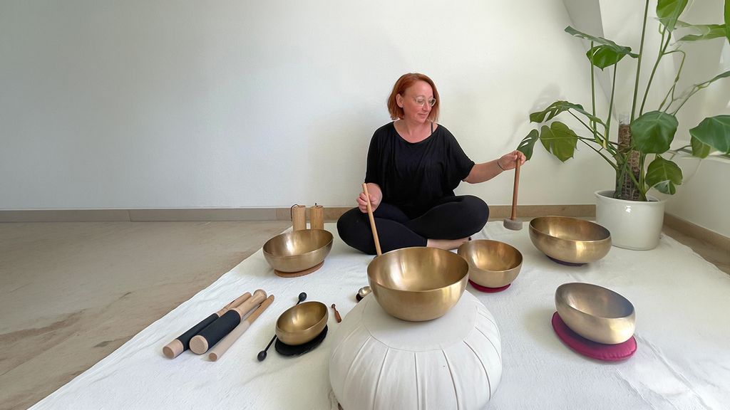 Eine Frau sitzend bei einer Klangschalen Einheit