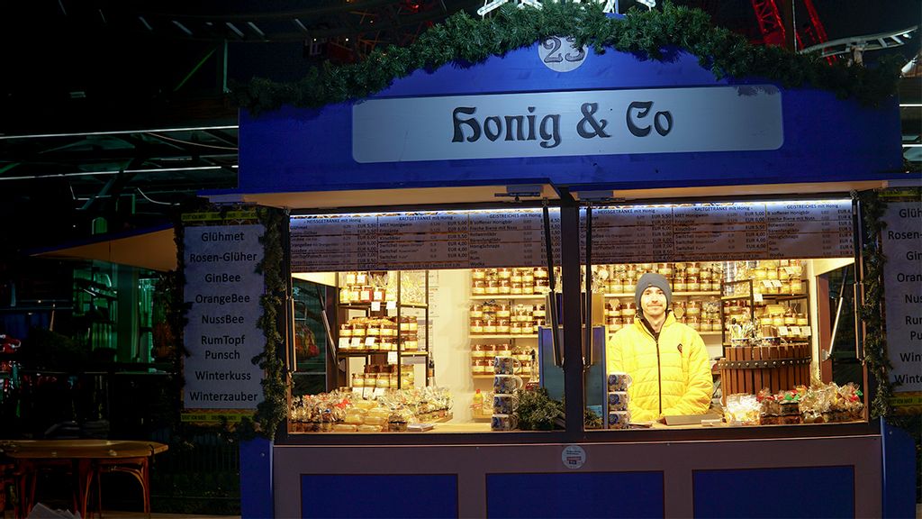 Weihnachtsmarkt-Stand bei Nacht mit Verkäufer hinter dem Tresen.