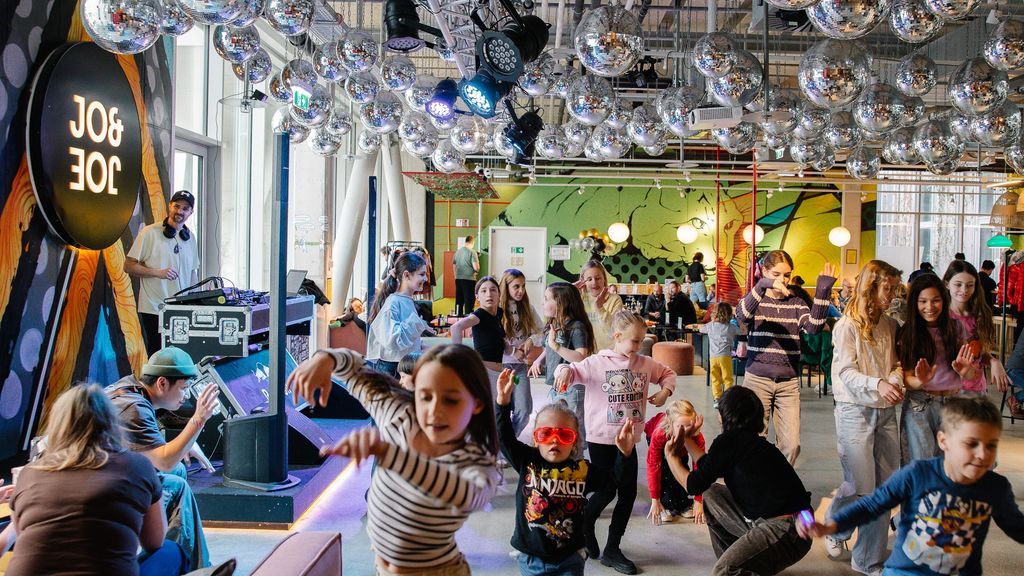 Kinder tanzen gemeinsam in einem bunt beleuchteten Raum