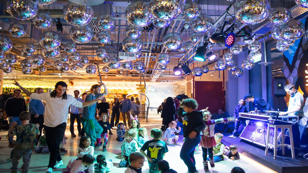 Kinder tanzen gemeinsam in einem bunt beleuchteten Raum