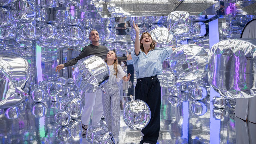 Eine Familie blickt auf viele Luftballons, die von der Decke hängen