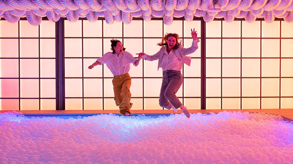 Zwei Frauen springen in ein Bällebad