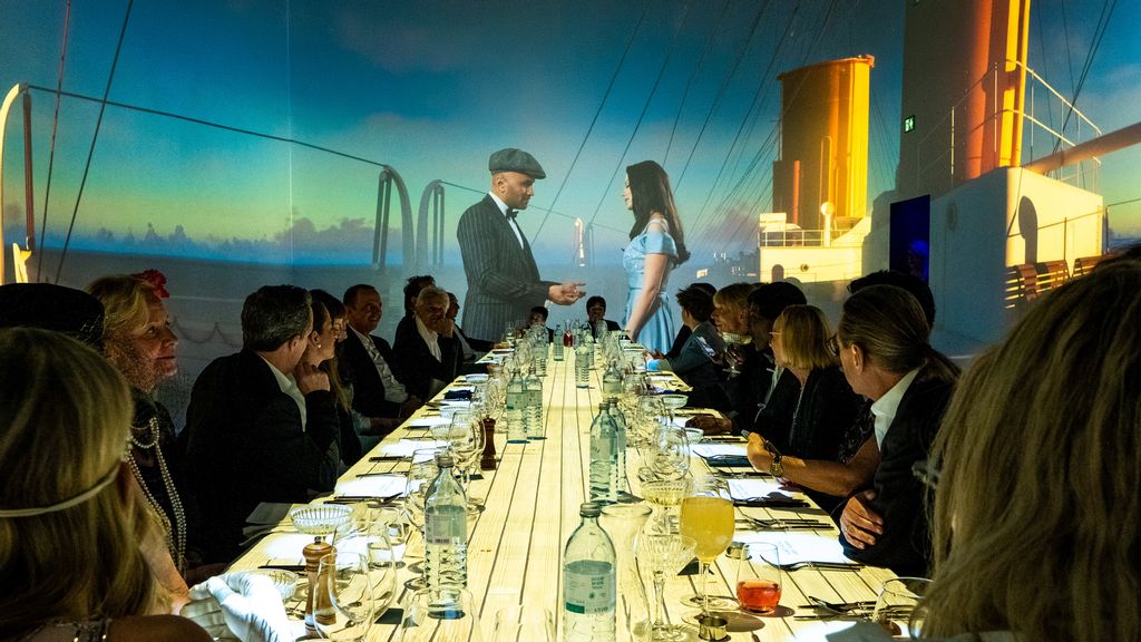 Immersives Dinner mit mehreren Personen, im Hintergrund sind Animationen auf der Wand