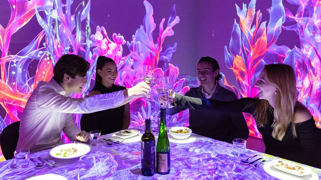 Immersives Dinner mit vier Personen, im Hintergrund sind Animationen auf der Wand