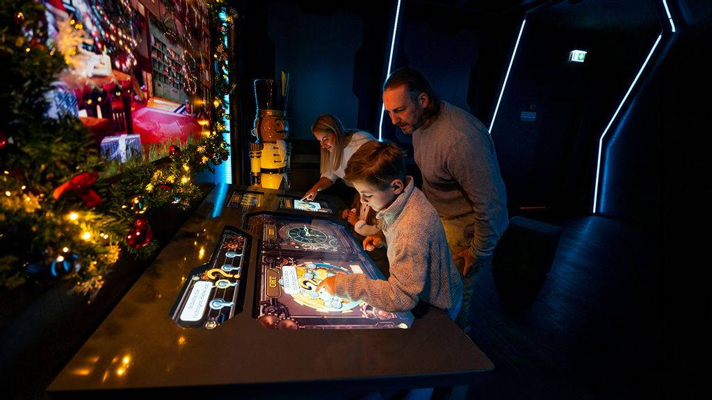 Eine Familie bei einem interaktiven Spiel mit weißen Kugeln in dunklem Raum