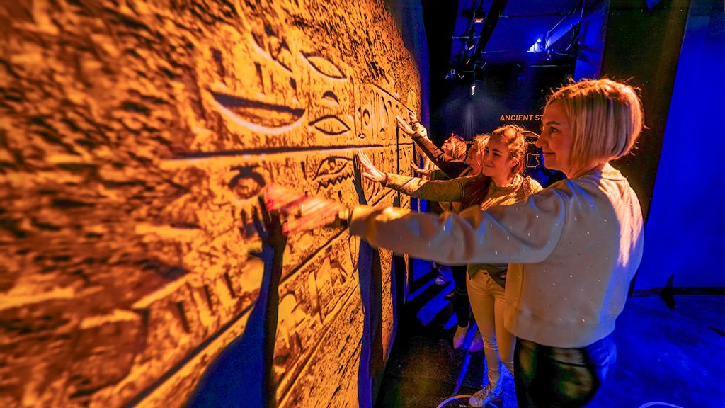 Besucher*innen bei einer immersiven Ausstellung bewundern eine Wand